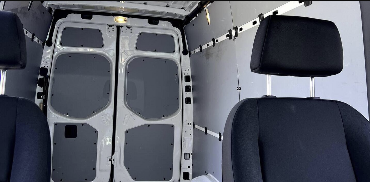 Rear cargo area & front seats of a clean van, ideal for RV rental conversions or transport.