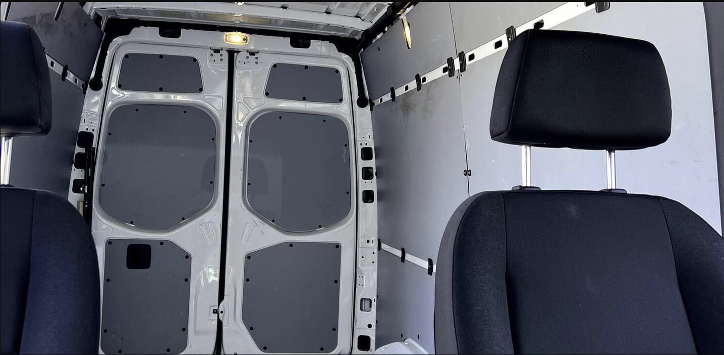 Rear cargo area & front seats of a clean van, ideal for RV rental conversions or transport.