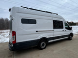 White Ford Transit camper van with custom tinted windows, roof rack & rear camera, ideal for rv rental adventures.