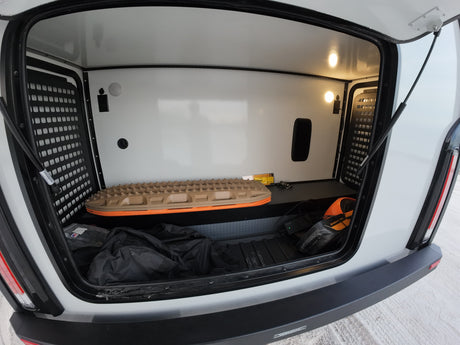 This RV rental's spacious storage compartment is equipped for adventure, featuring a recovery board, Onewheel, and organized gear.