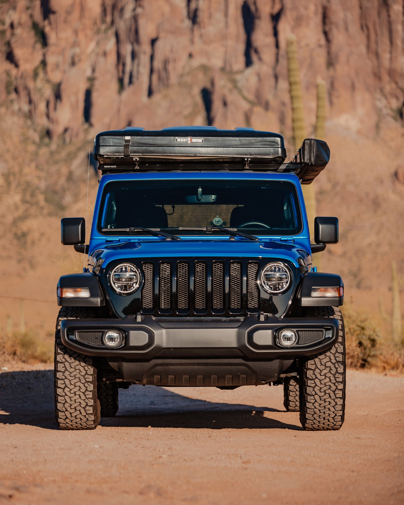 This blue Jeep, equipped with a rooftop tent for off-road rv rental adventures, is ready for desert exploration.