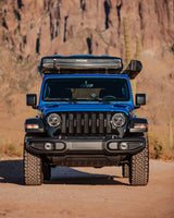 This blue Jeep, equipped with a rooftop tent for off-road rv rental adventures, is ready for desert exploration.