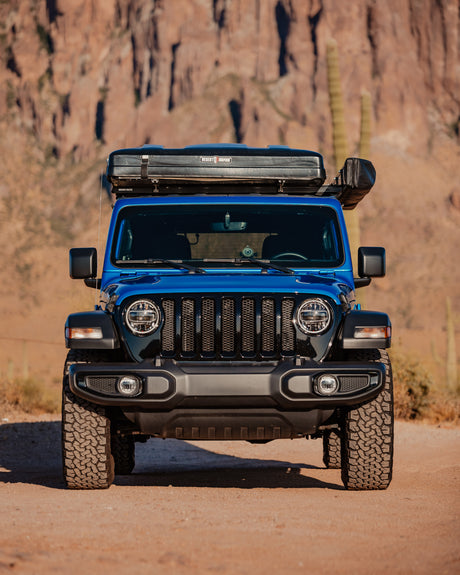 This blue Jeep, equipped with a rooftop tent for off-road rv rental adventures, is ready for desert exploration.