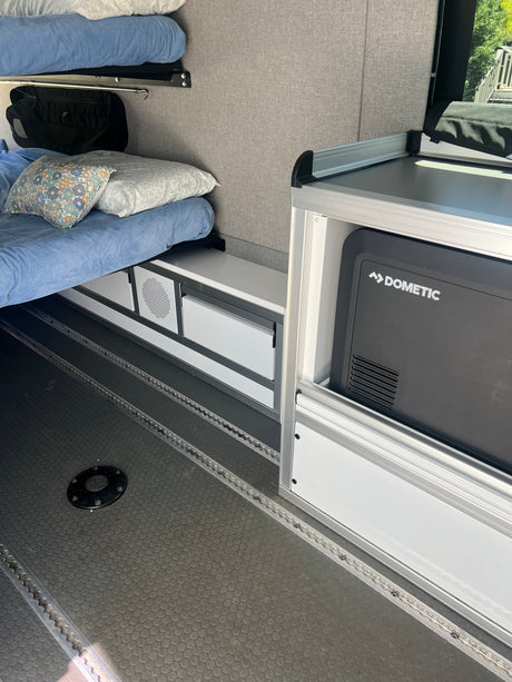 RV rental: Camper interior showcasing bunk beds, integrated storage, and a Dometic fridge on textured L-track flooring.