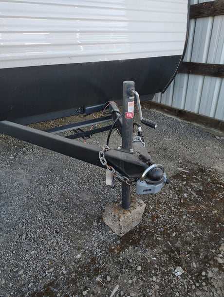  is parked on gravel in a storage shed with its door open.|A Coleman RV rental