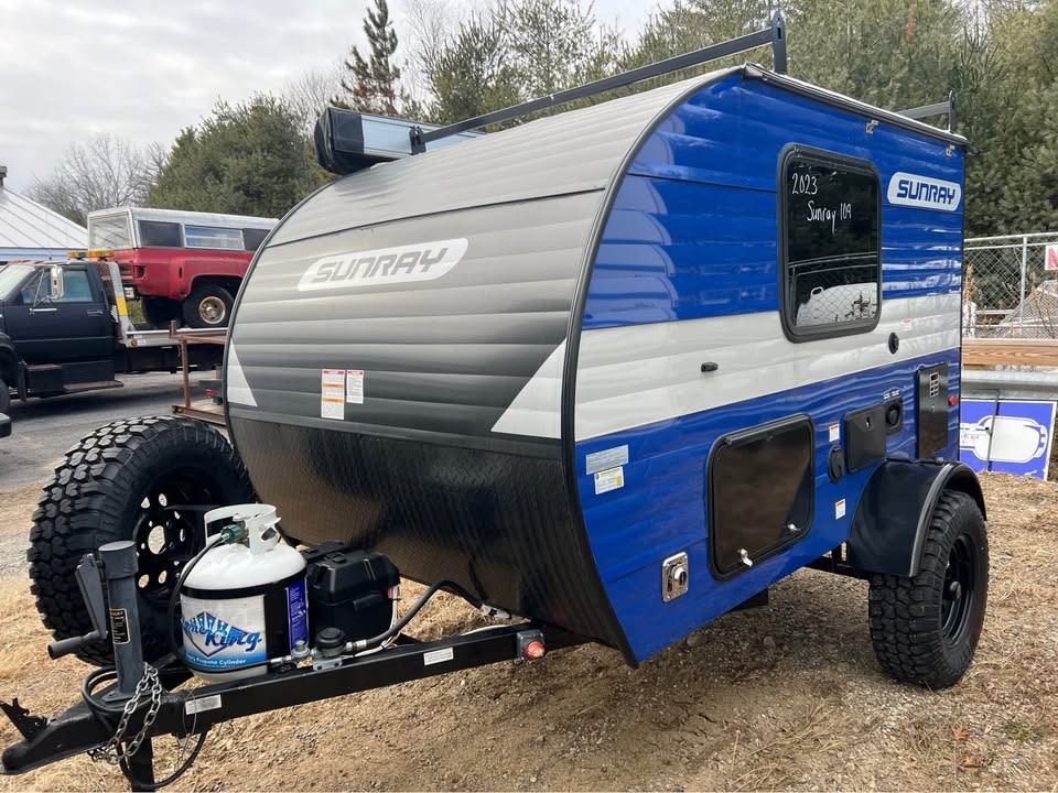  parked near a larger motorhome. Ideal for camping.|Compact blue & black Sunray teardrop trailer — photo 3