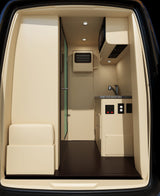 Luxury RV rental interior with beige walls, a compact kitchen, and a comfortable bench seat.