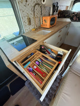 This RV rental kitchen features smart storage with an organized utensil drawer, induction cooktop, and a fun retro microwave.