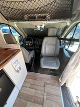 RV rental camper van interior. Front cabin view from living space, showing wood floor, sunshade, and overhead net.
