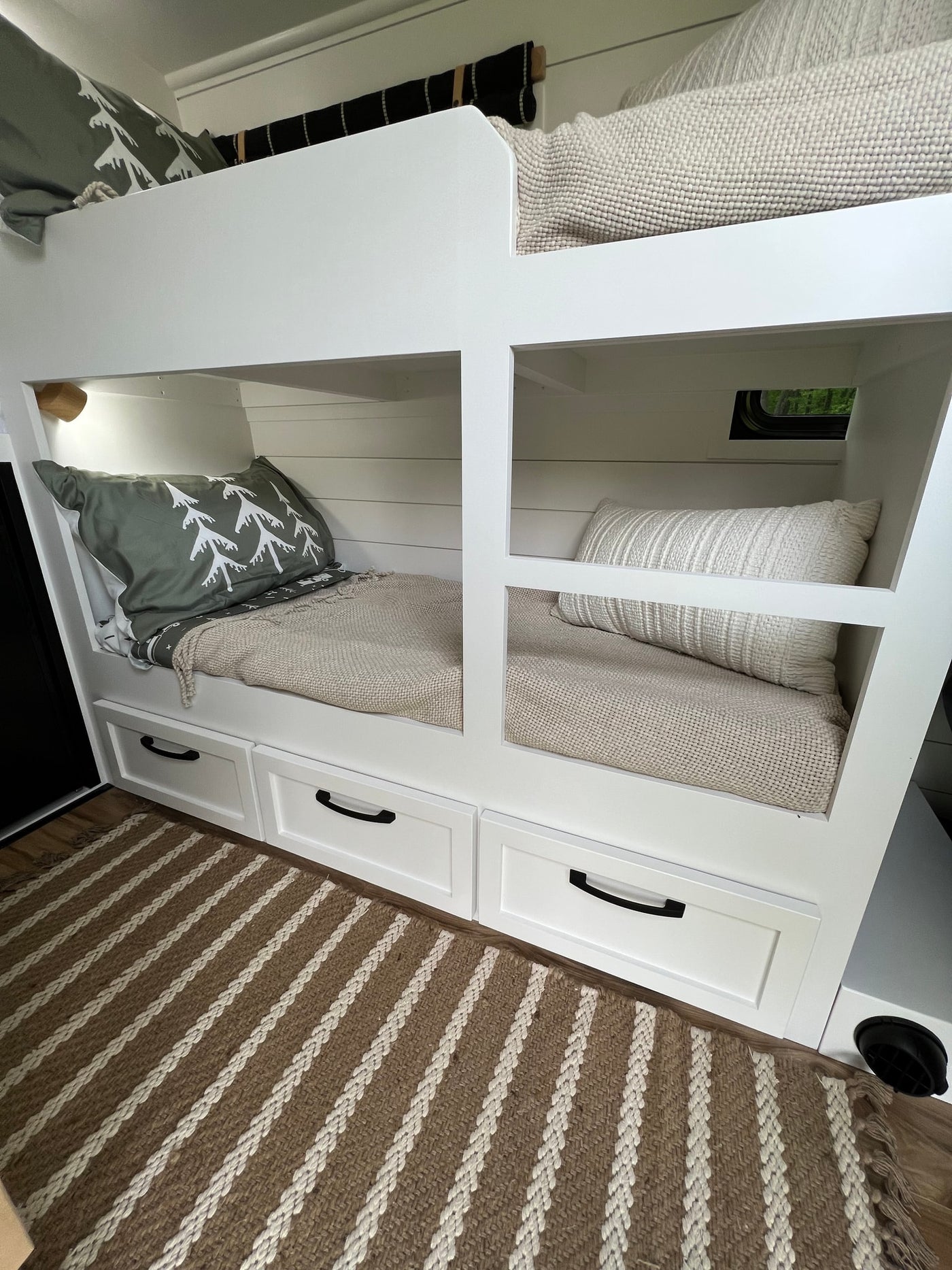 Cozy RV rental bunk beds with built-in storage and neutral decor, featuring a window and striped rug, maximize space for travel. — photo 11