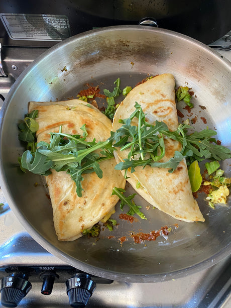 Quesadillas with arugula in a pan on an RV rental stove, ready for a camp meal.