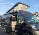 Dark grey camper van with pop-top roof extended, side door open showing interior. Ideal for your next RV rental.