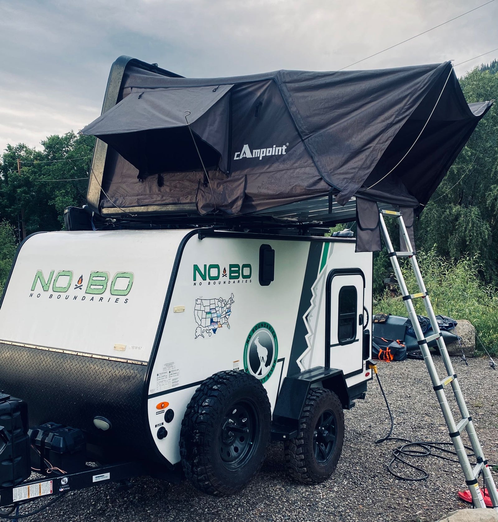Adventure-ready RV rental: A NO BO travel trailer with a deployed Campoint rooftop tent, perfect for off-grid camping.