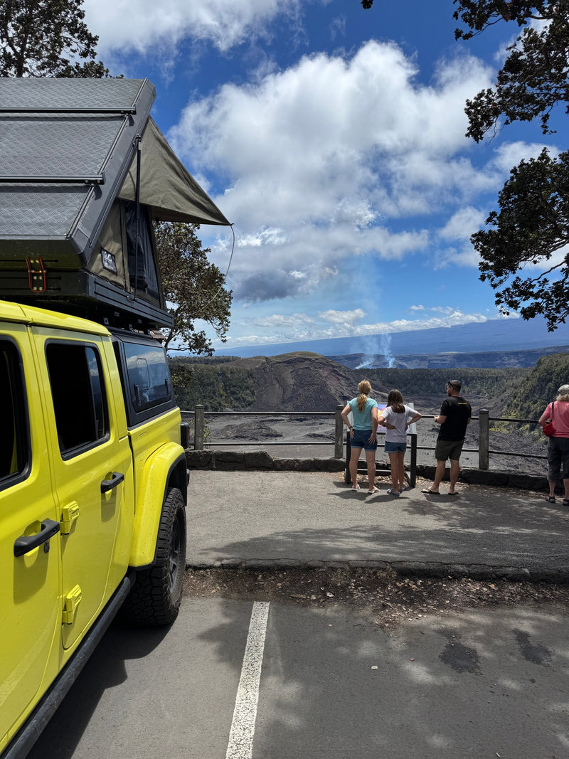 Yellow rv rental Jeep & rooftop tent at a volcano overlook. Visitors watch the steaming crater against a cloudy sky. — photo 7