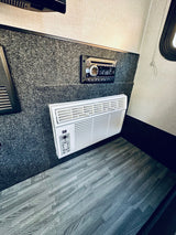 RV rental: Inside, a stereo and AC unit are mounted on carpeted walls above wood-look flooring.