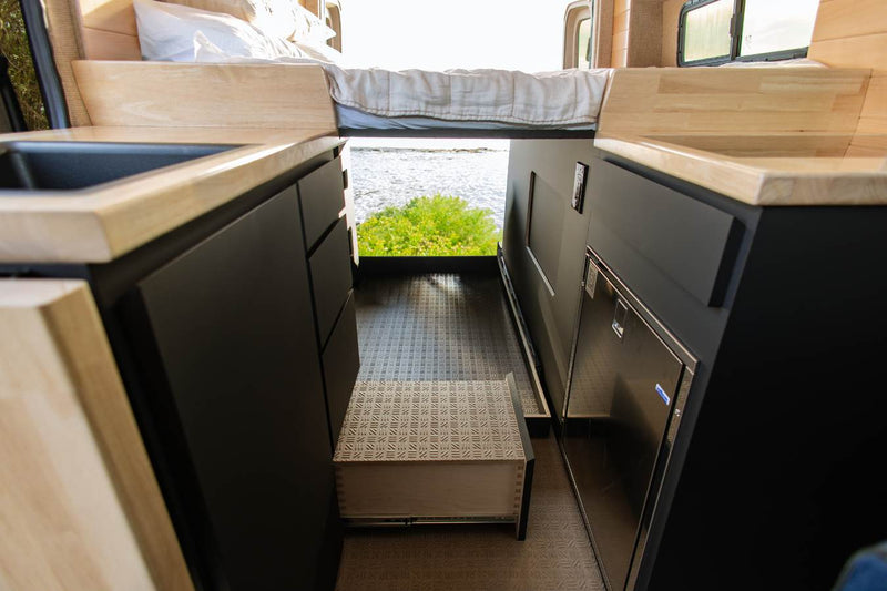  and desert views. Wood panels and black cabinets are visible.|Modern camper van interior from the side door. This RV rental offers a kitchen — photo 11