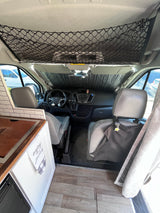 Inside this RV rental camper van: a neat cockpit with sunshade, overhead net, and a compact kitchen. Ready for adventure!