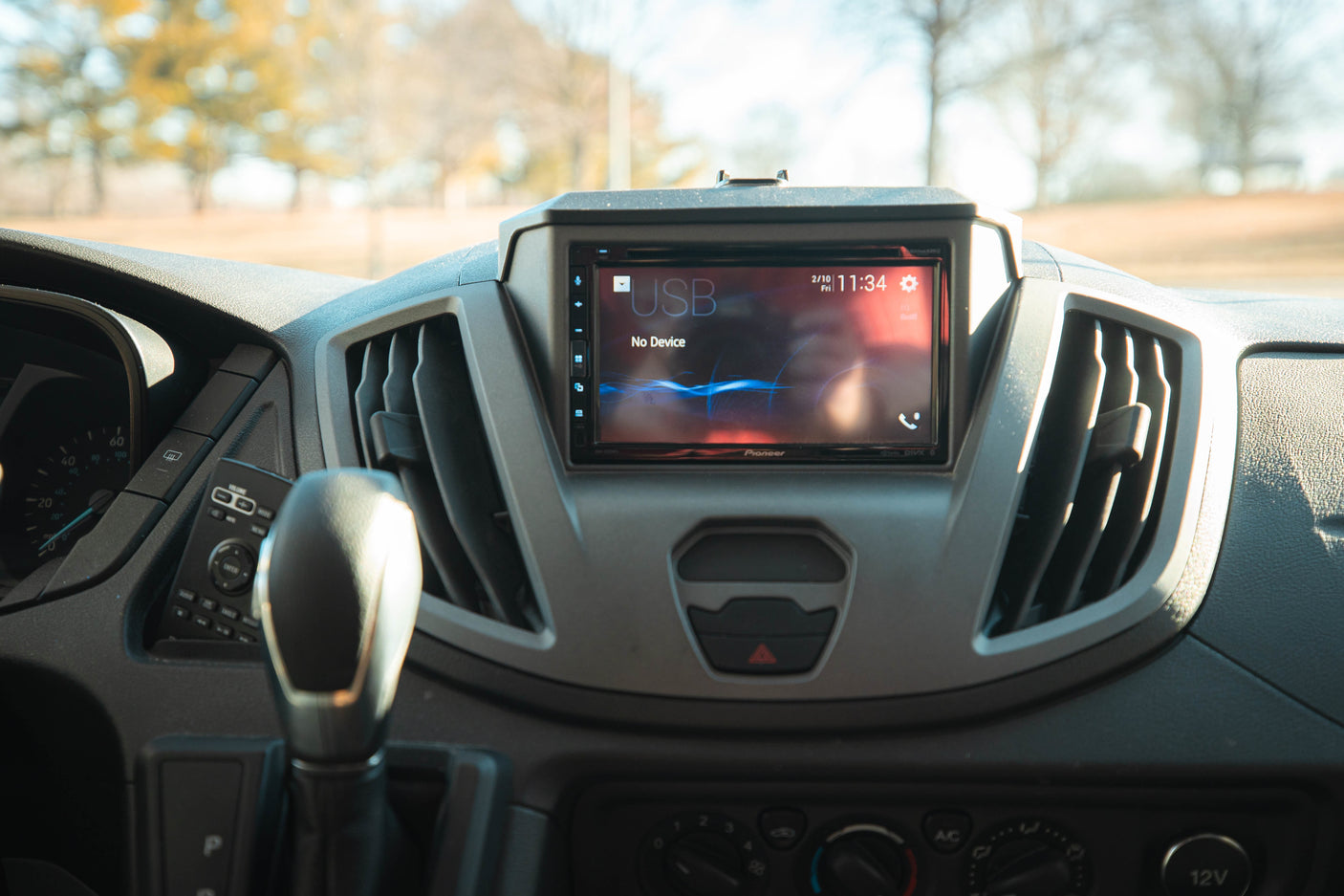 Inside an RV rental: a modern dashboard featuring a Pioneer infotainment screen, climate controls, and gear shift.