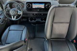 View of a modern rv rental front cabin: black leather seats, dashboard with navigation screen, and steering wheel.