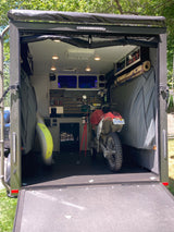 Custom adventure trailer interior with dirt bike, paddleboard, and organized storage. Ideal for RV rental trips.