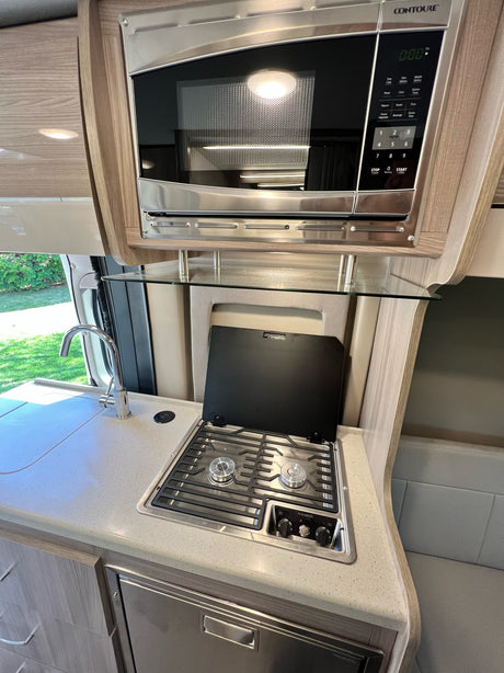This RV rental's modern kitchen boasts a microwave, two-burner stove, and sink. Ideal for travel culinary adventures.