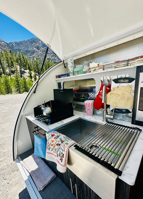RV rental galley kitchen with sink, stovetop, and mountain views. Perfect for camping adventures.
