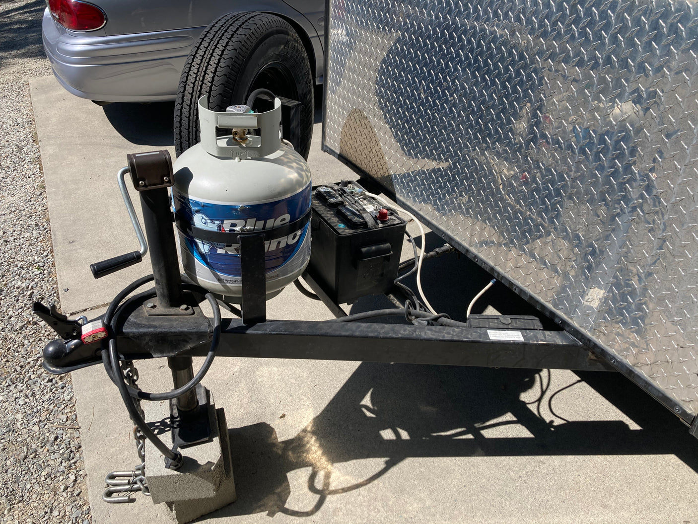 Essential components for an RV rental trip: A trailer's hitch, propane tank, and battery, ready for towing.