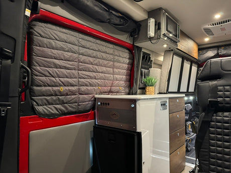 Explore this modern rv rental interior, featuring an equipped kitchenette, cozy seating, and insulated window shades.