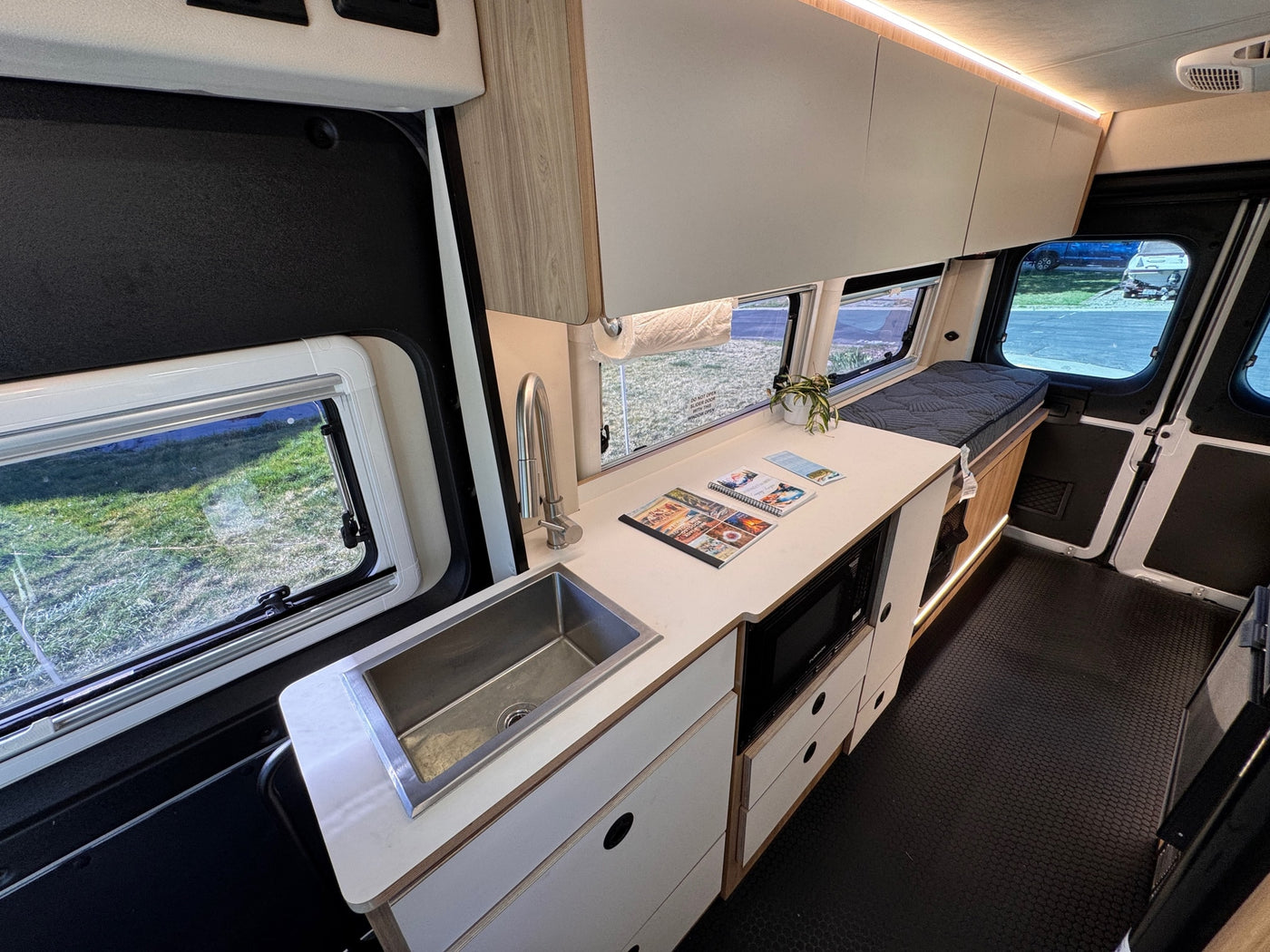 This rv rental features a modern camper van interior with a kitchenette, sink, microwave, and comfortable sleeping area. — photo 14