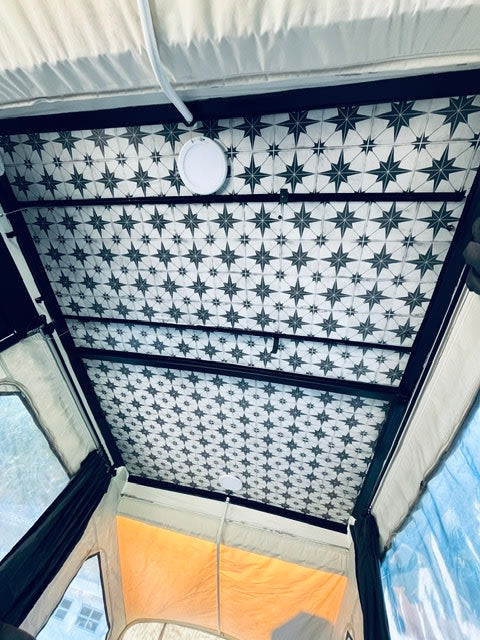Unique RV rental ceiling: black and white star pattern, central LED light. Cozy camper interior design for your travels.