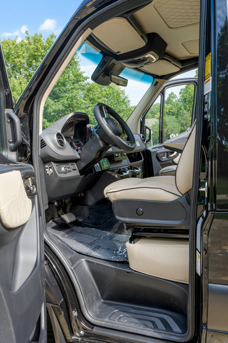 Inside this rv rental: a pristine driver's cockpit with cream leather seat, detailed dashboard, and visible pedals.