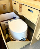 RV rental interior with a white Porta Potti portable toilet, custom wood drawers, and clever compact storage solutions.