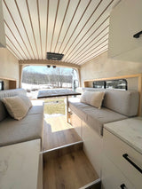 Cozy RV rental interior with comfortable seating, dining table, and scenic winter outdoor view. Ideal mobile living space.