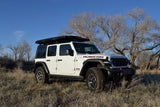 White Jeep Wrangler Rubicon with roof-top tent, perfect for an RV rental camping adventure in nature.