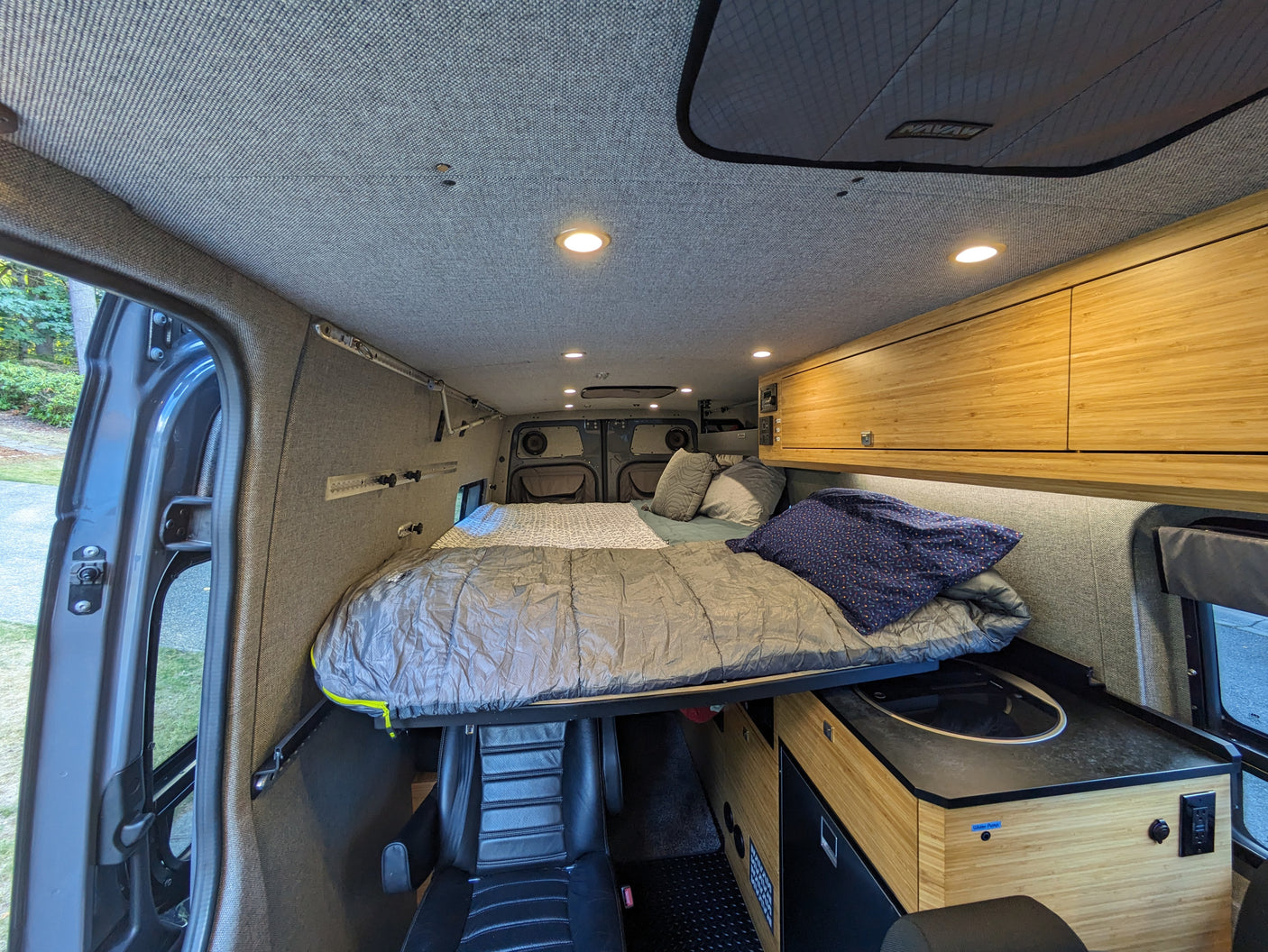 Spacious RV rental interior features a cozy elevated bed, bamboo kitchen cabinets, and functional living space.