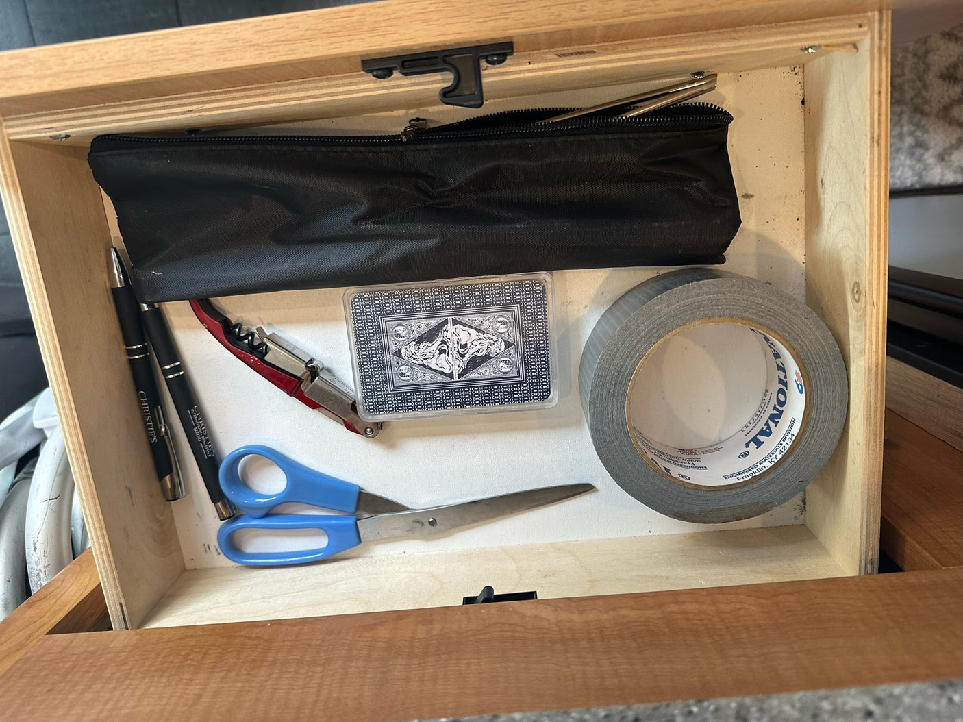 "RV rental" compact storage drawer, neatly organized with pens, playing cards, duct tape, scissors, and a multi-tool.