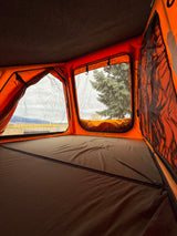 Inside a vibrant orange rooftop tent with a comfy bed & scenic mountain views. Ideal for your RV rental trip.