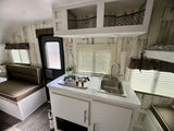 RV rental: Bright, functional interior features kitchenette with stove & sink, dinette, and overhead storage.