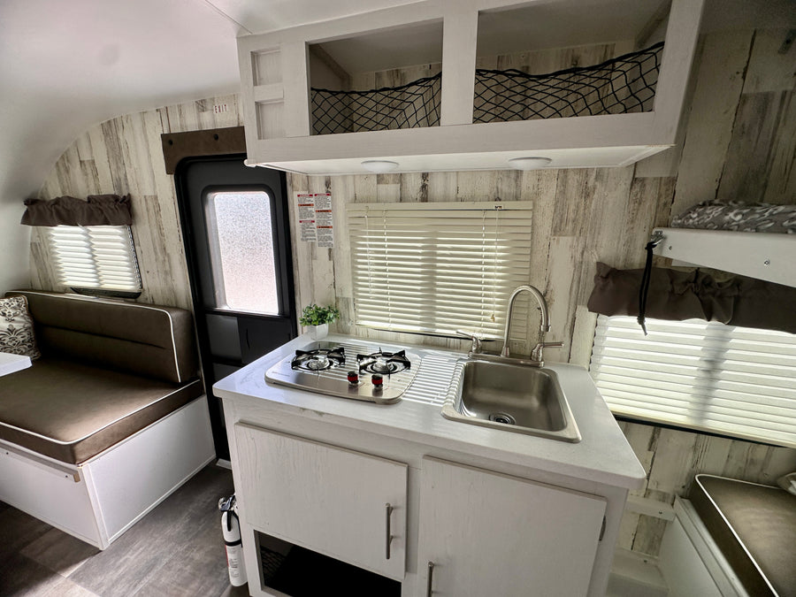 RV rental: Bright, functional interior features kitchenette with stove & sink, dinette, and overhead storage.