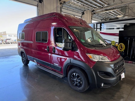 Discover this sleek burgundy camper van, perfect for your RV rental needs. Parked inside, ready for travel.
