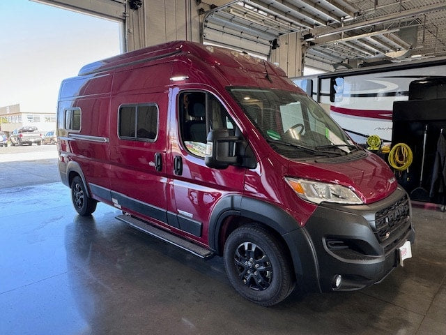  is seen from the rear 3/4 view while parked indoors.|Discover this sleek burgundy camper van — photo 3