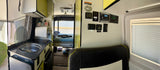 Explore this compact rv rental interior, featuring a kitchen, cozy bed area, and complete control panel for all systems.