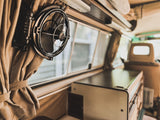 Inside a retro rv rental: chrome fan, soft curtains, & compact kitchenette offer a cozy travel experience.