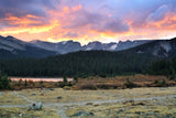 Golden & purple sunset over mountains, a tranquil lake, & pine forest. Plan your adventure with an RV rental!