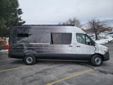 Custom Mercedes-Benz Sprinter van rv rental, featuring unique topographic map graphics, parked on an asphalt lot.