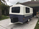 Compact, two-tone camper trailer, great for your next RV rental adventure, parked on a driveway.