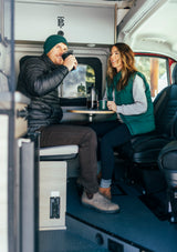 Happy couple shares a coffee moment inside a comfortable rv rental. Ideal for travel & adventure in a cozy camper van.
