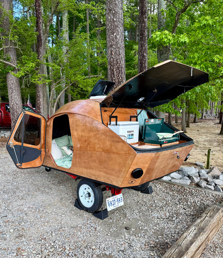 Unique wooden teardrop RV rental with open rear kitchen & cozy interior. Perfect for camping in this Virginia wooded site.