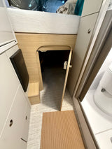 RV rental interior: View of an overhead bed, under-bed storage access, and a peek into the compact bathroom.