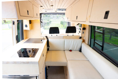 This cozy RV rental interior features a modern kitchenette, comfortable L-shaped seating, and smart overhead storage.
